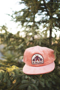 Be The Light Hat resting on a tree branch, showcasing its corduroy design and vivid embroidery.