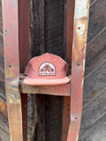 Be The Light Hat displayed on a rustic rack, showcasing its unique design and message.