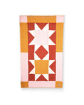 Bernie Blanket with a quilt-style star pattern in pink, rust, gold and white