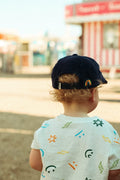 Child wearing a Big Fan Of Fun Kids Hat, enjoying a sunny day outdoors.