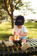 Toddler wearing Big Fan Of Fun Kids Hat while enjoying a drink on a sunny day outdoors.