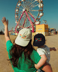 Two people wearing Big Fan Of Fun Hat - Twinsie Set enjoying a carnival scene with a ferris wheel.