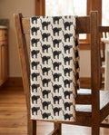 Black Cats waffle kitchen tea towel draped over a wooden kitchen chair, front print facing out