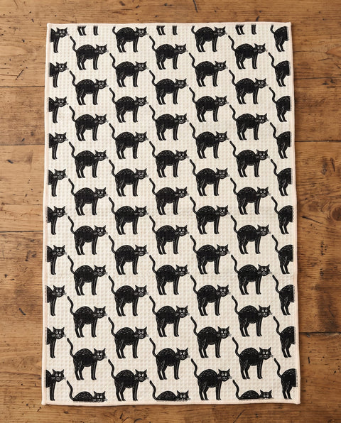 Black Cats waffle kitchen tea towel laid flat on a wood counter showing the full front print