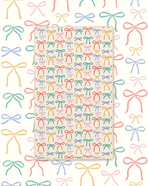 Holiday Bows Kitchen & Tea Towel with colorful hand-drawn bows in red, green, blue and pink on cream