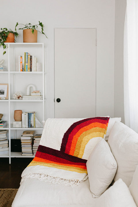 Cozy Trek Light Bowie Blanket draped on a sofa, showcasing vintage rainbow design for sustainable and stylish comfort.