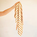 Calendula Flowers Kitchen & Tea Towel being held, showcasing its vibrant double-sided design and striped pattern.