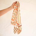 Calendula Flowers Kitchen & Tea Towel held in hand, showcasing vibrant floral and striped design.