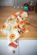 California Kitchen & Tea Towel with vibrant orange poppy design on a wooden kitchen counter.