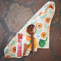 California Kitchen & Tea Towel with vibrant designs and a wooden spoon on a rustic stone surface.