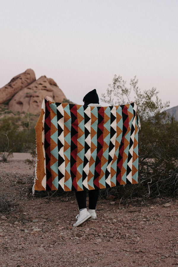 Cozy Cascade Blanket handwoven from recycled clothing materials, featuring beautiful geometric patterns in a versatile outdoor setting. By Trek Light.