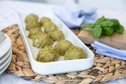 Plated broccoli and cheese bites with fresh basil on a wooden board for a healthy snack option.