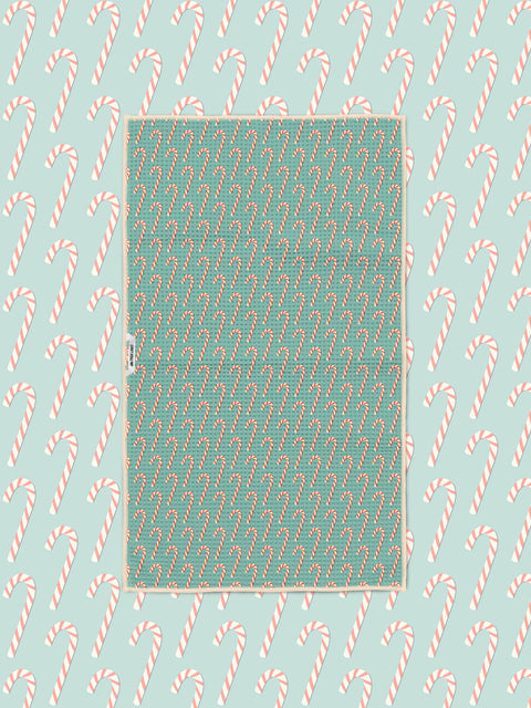 Candy cane print kitchen tea towel styled on a matching teal candy cane backdrop