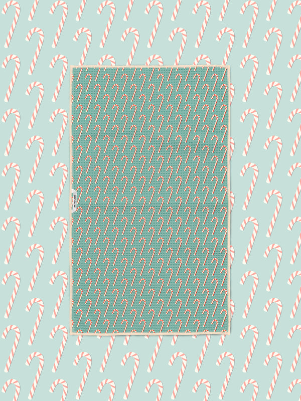 Candy cane print kitchen tea towel styled on a matching teal candy cane backdrop