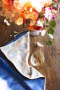 Coastal Oysters Kitchen & Tea Towel displayed with a floral arrangement and glass on a wooden table.