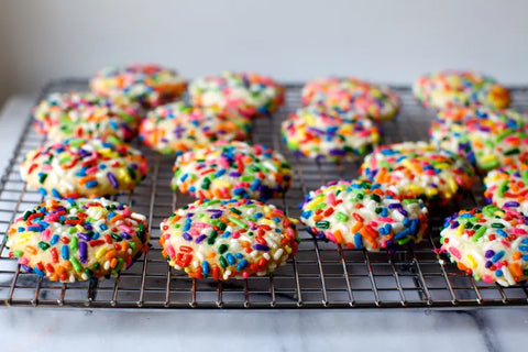 Freshly baked cookies topped with colorful sprinkles cooling on a wire rack.