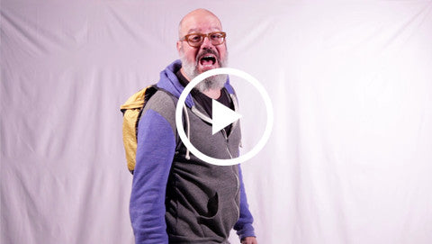 Person wearing Trek Light backpack, enthusiastically demonstrating its features in front of a white background.