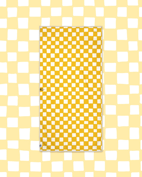 Desert Dreams Wander & Travel Towel in yellow and cream checkerboard print, laid flat on a pale yellow checked background.