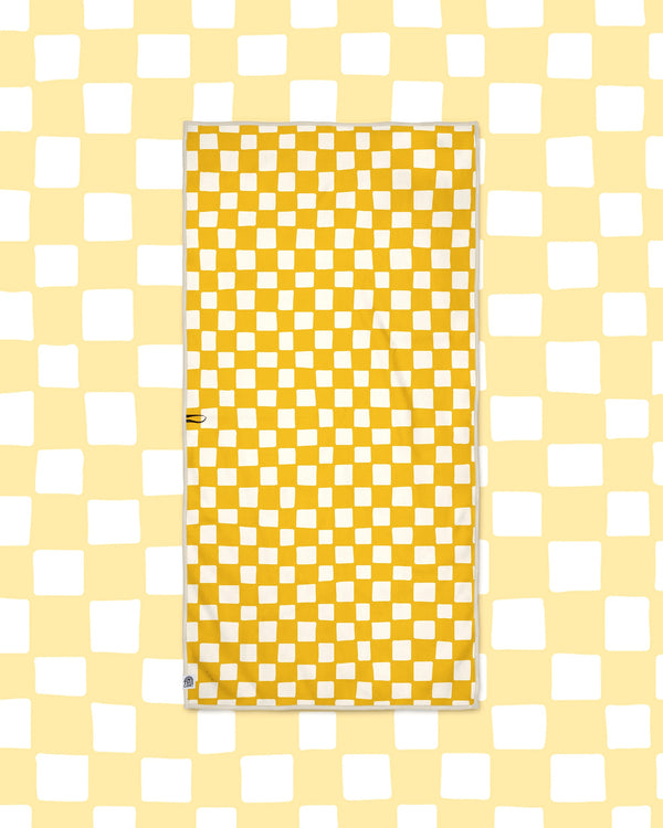 Desert Dreams Wander & Travel Towel in yellow and cream checkerboard print, laid flat on a pale yellow checked background.