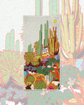 Desert Dreams Wander & Travel Towel with a colorful cactus print on cream, set over a faded pink and green cactus pattern