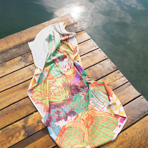 Colorful Trek Light towel on a wooden dock by a serene lake, soaking up sunshine and adventure-ready vibes.