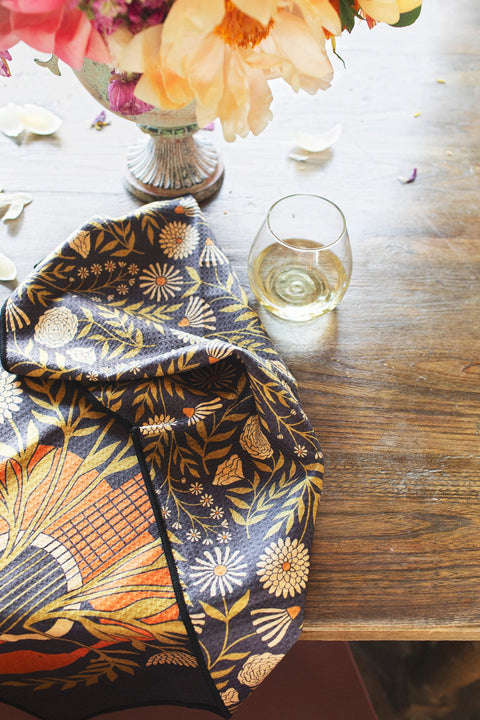 Dinner Music Kitchen & Tea Towel draped on a table, surrounded by flowers and a glass of wine.