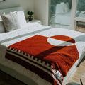 Rust and white divided sky blanket on bed, handwoven from recycled materials, by Trek Light. Eco-friendly and artisan-crafted.