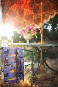 Ducks In A Row Kitchen & Tea Towel draped over a chair next to a table with flowers, showcasing vibrant duck designs.