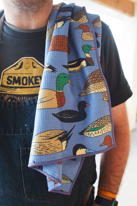 Ducks In A Row Kitchen & Tea Towel featuring colorful duck illustrations on a vibrant blue background.