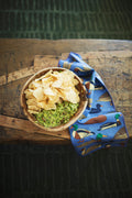Ducks In A Row Kitchen & Tea Towel next to a bowl of guacamole and tortilla chips on a wooden table.
