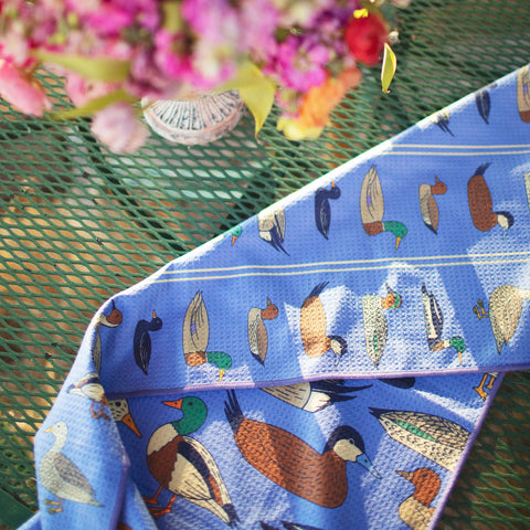 Ducks In A Row Kitchen & Tea Towel featuring vibrant duck illustrations on a blue background.