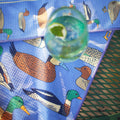 Ducks In A Row Kitchen & Tea Towel with colorful duck designs and a glass of drink on a table.
