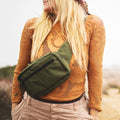 Woman wearing Everyday Fanny Pack (Fern) as a crossbody sling outdoors, showcasing versatile design and spacious capacity.