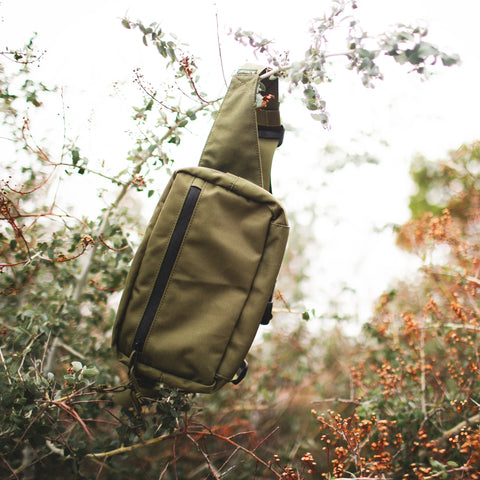 Everyday Fanny Pack (Fern) hanging on branches, showcasing waterproof and versatile design ideal for travel and daily use.