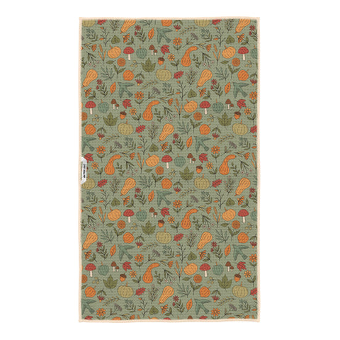 Fall Harvest kitchen tea towel on sage green background with orange pumpkins, gourds, mushrooms, acorns, leaves and birds