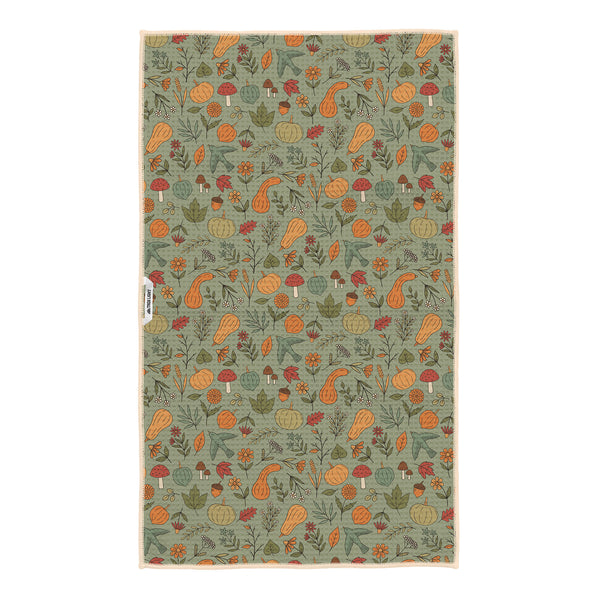 Fall Harvest kitchen tea towel on sage green background with orange pumpkins, gourds, mushrooms, acorns, leaves and birds