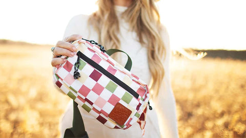 Colorful checkered Everyday Fanny Pack by Trek Light held by a person in a sunny field