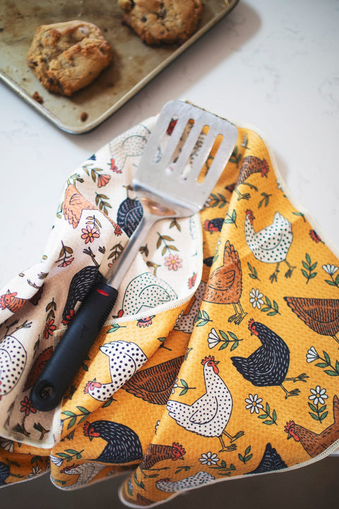 Farmhouse Chicken Kitchen & Tea Towel with decorative chicken patterns and a spatula on a marble countertop.