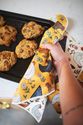 Farmhouse Chicken Kitchen & Tea Towel being used to grab cookies from a baking tray, featuring colorful chicken designs.