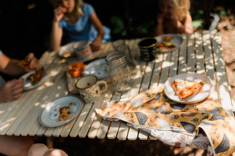Farmhouse Chicken Kitchen & Tea Towel resting on a table during a family meal outdoors.