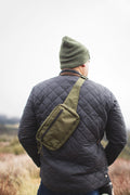 Man wearing Everyday Fanny Pack (Fern) as a crossbody sling, showcasing its versatility in outdoor setting.