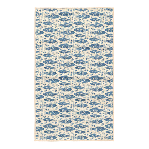 Beige kitchen tea towel covered in blue floral trout fish arranged in rows with small white flowers between them