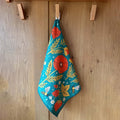 Eco-friendly Garden Buzz kitchen dish towel with vibrant floral and bee design, hanging on a wooden hook. Super absorbent.