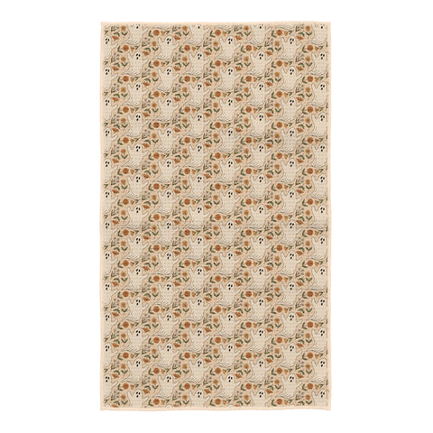 Ghost Garden kitchen tea towel in cream with white ghosts, orange marigolds and green leaves, hanging loop at corner