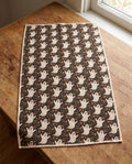 Ghost Garden kitchen tea towel reverse side laid flat, dark brown with cream ghosts and orange flowers