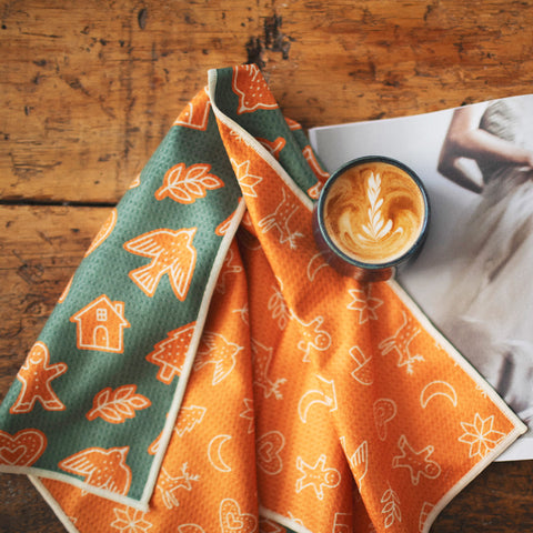 Gingerbread Kitchen & Tea Towel with vibrant double-sided design, eco-friendly recycled materials, and quick-dry Grip-Tex™ fabric, on wood table.