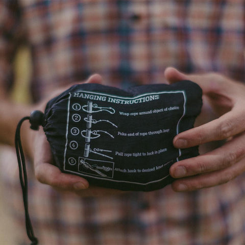 Person holding Trek Light gear with clear hanging instructions printed on a pouch, ready for adventure.