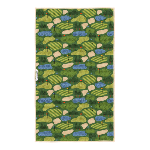 Close-up of Golf Dreams tea towel design showing detailed illustrations of striped fairways, putting greens, trees, and golf holes in vibrant green and yellow tones