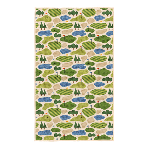Golf Dreams kitchen tea towel with repeating pattern of green golf courses, sand bunkers, blue water hazards, and red flags on cream background
