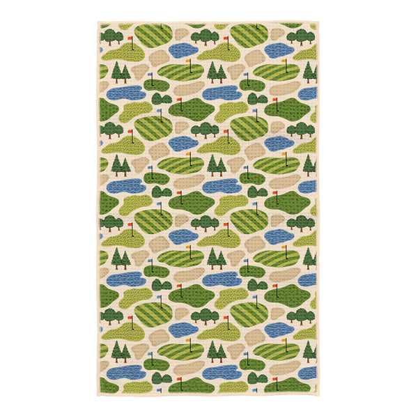 Golf Dreams kitchen tea towel with repeating pattern of green golf courses, sand bunkers, blue water hazards, and red flags on cream background